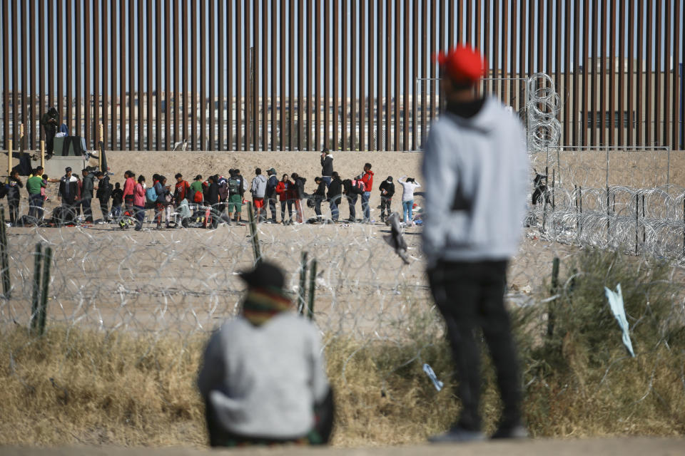 Migrantes hacen fila junto al muro fronterizo con Estados Unidos después de ser detenidos por las autoridades migratorias estadounidenses, vistos desde el lado de Ciudad Juárez, México, el 27 de diciembre de 2023. (AP Foto/Christian Chávez)