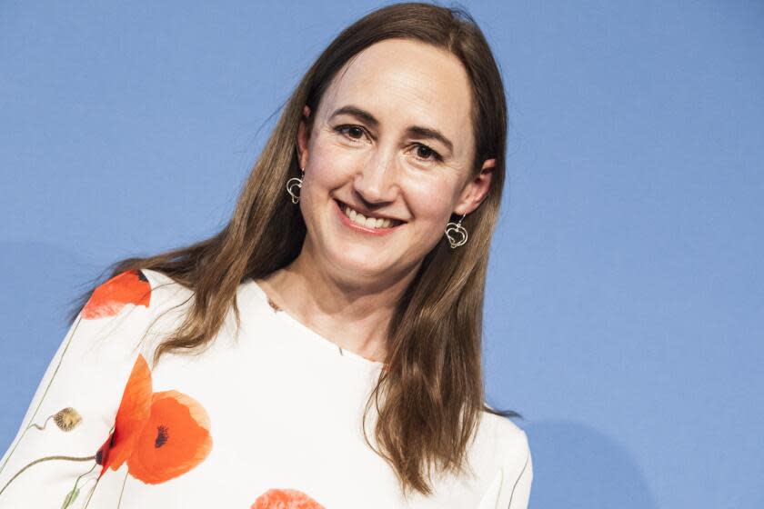 Author Sophie Kinsella smiles while wearing a white dress with red blooms on it