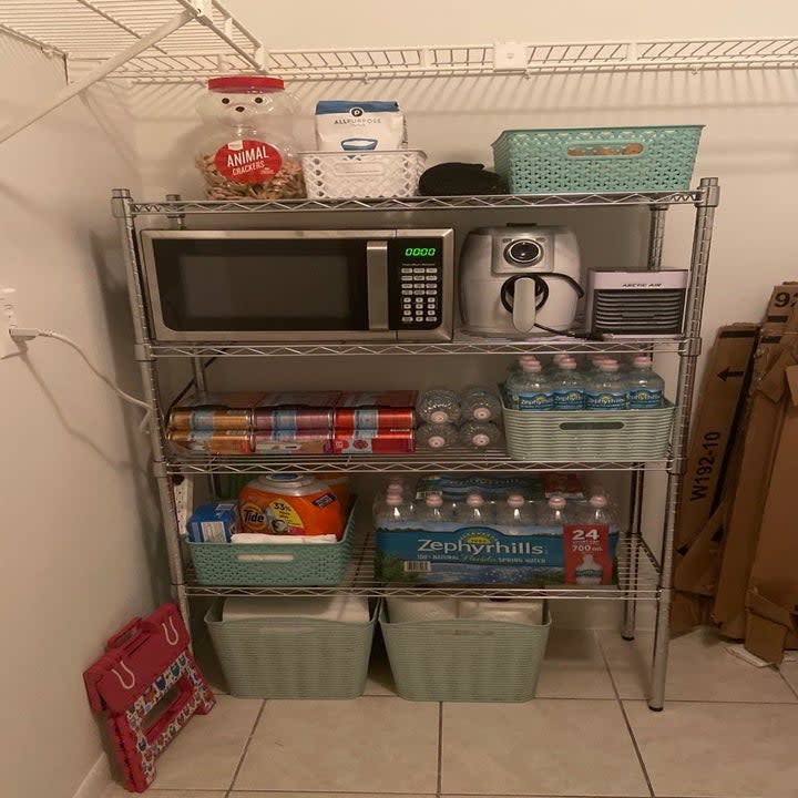 reviewer photo showing shelf used in their kitchen with microwave and food stored on it 