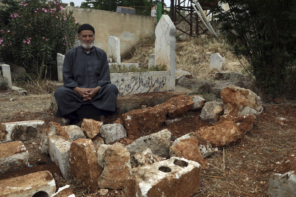 Mohammed Hassan Misto sits next to the grave of his brother Lotfi.