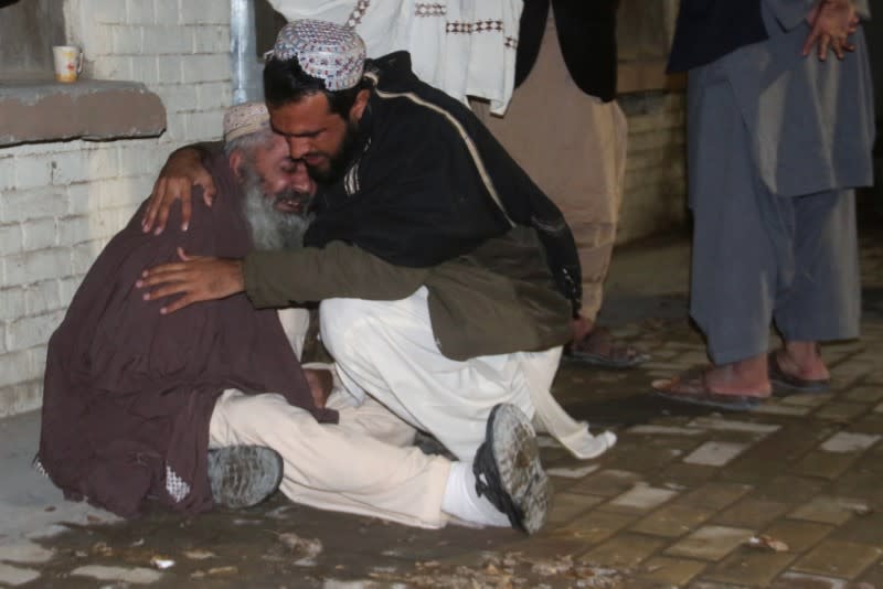 Men comfort each other as they mourn the death of a relative who was killed in a bomb blast in a mosque, at a hospital morgue in Quetta,