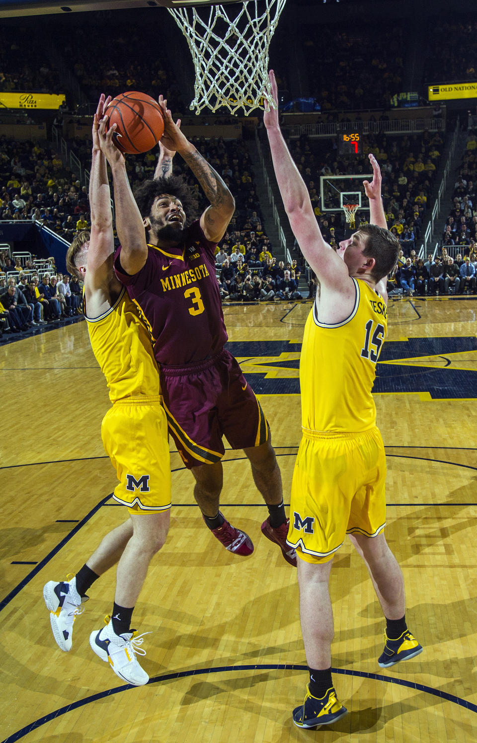 Minnesota forward Jordan Murphy (3) tries to make a basket, defended by Michigan forward Ignas Brazdeikis, left, and center Jon Teske (15), in the second half of an NCAA college basketball game at Crisler Center in Ann Arbor, Mich., Tuesday, Jan. 22, 2019. Michigan won 59-57. (AP Photo/Tony Ding)
