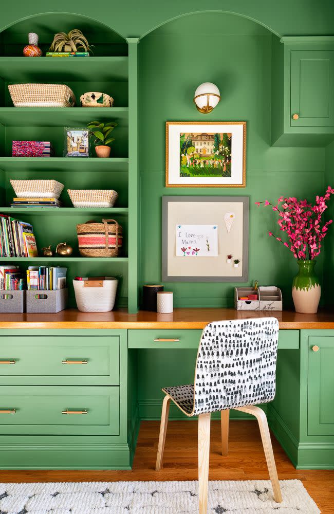 a green room with a chair and a shelf with books on it