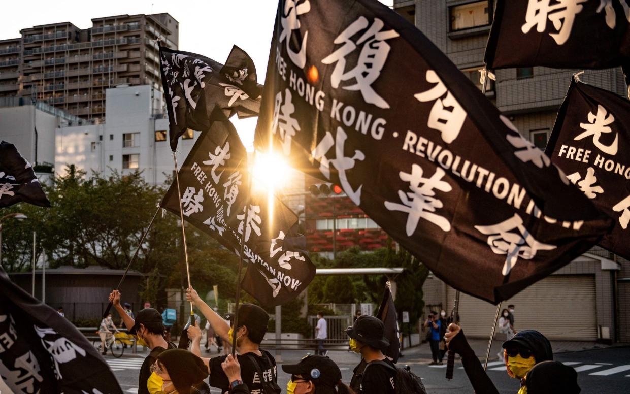 Activists wave Hong Kong protest flags during a rally calling for a boycott of the Beijing 2022 Olympic Games over China's human rights record, in Tokyo - Philip Fong/AFP 