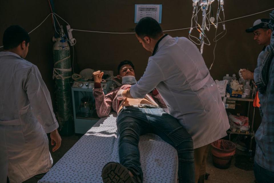 An injured man is assisted by medics in a field hospital set up along the Gaza-Israel border.