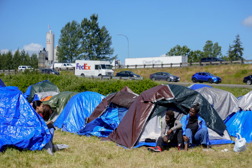 Eduardo Afonso, 15, of Angola, sits with sister Miria Rainha next to their tent at an encampment of asylum-seekers mostly from Venezuela, Congo and Angola next to an unused motel owned by the county, Wednesday, June 5, 2024, in Kent, Washington. The group of about 240 asylum-seekers is asking to use the motel as temporary housing while they look for jobs and longer-term accommodations. (AP Photo/Lindsey Wasson)