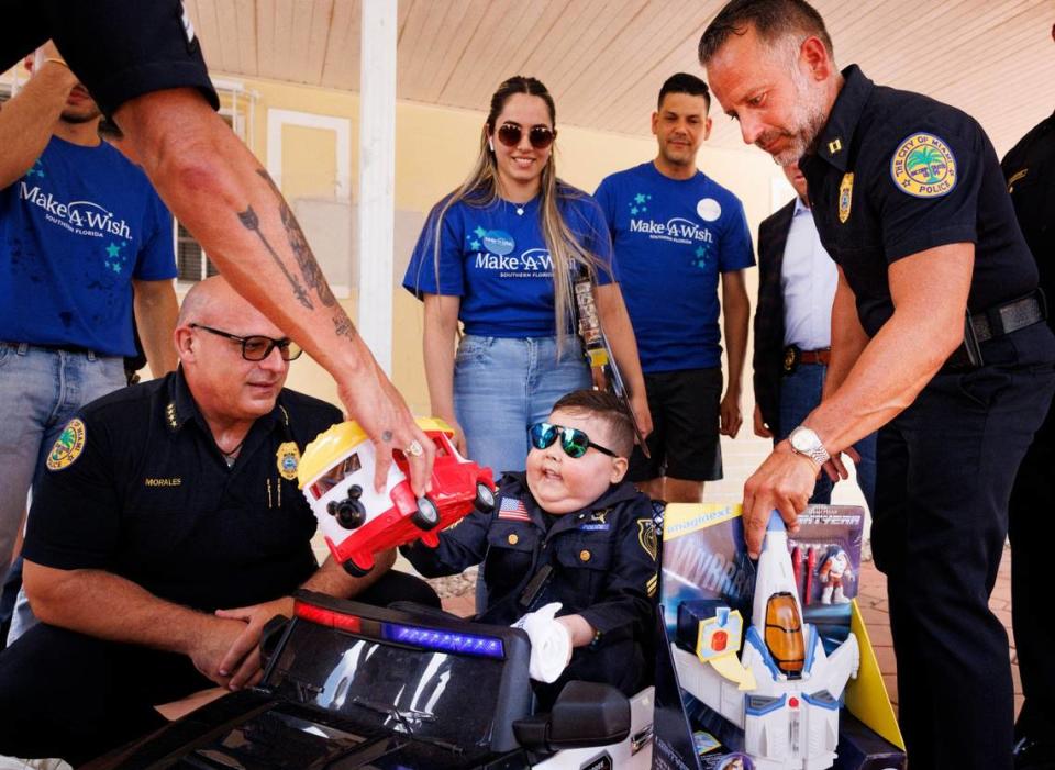 Franco Bernal, center, 6, battling childhood leukemia, receives gifts from Manny Morales, City of Miami Chief of Police, left, and Freddie Cruz, right, during his Wish Reveal announcing his trip to Disney World on Thursday, July 18, 2024, with a parade by Make-A-Wish and City of Miami Police in Miami.