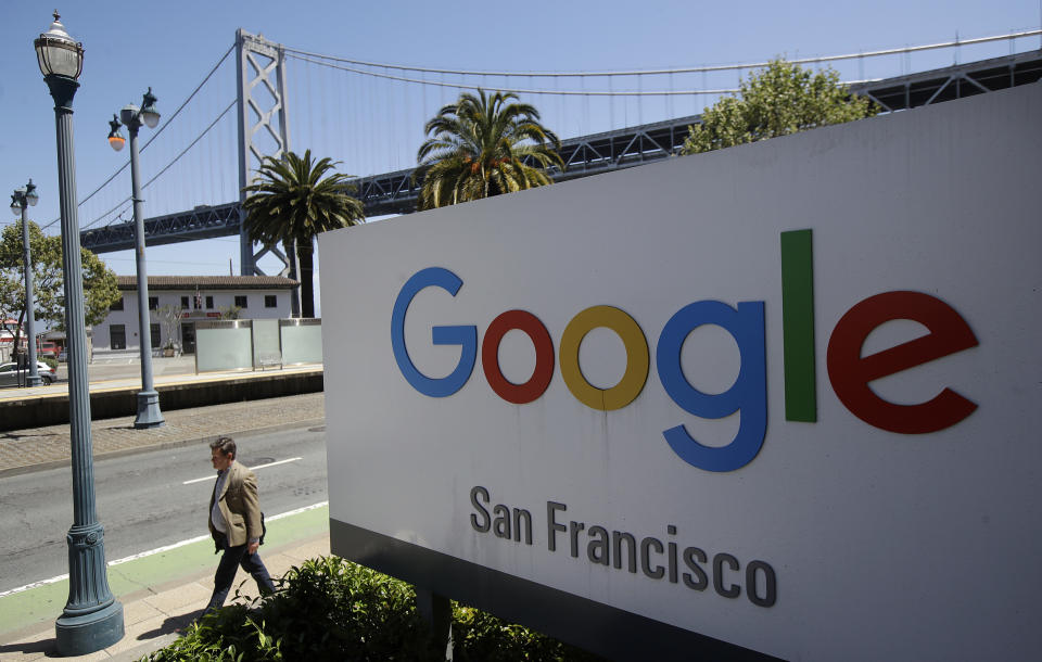 FILE - In this May 1, 2019, file photo a man walks past a Google sign outside with a span of the Bay Bridge at rear in San Francisco. A group of states are expected to announce an investigation into Google on Monday, Sept. 9, to investigate whether the tech company has become too big. (AP Photo/Jeff Chiu, File)