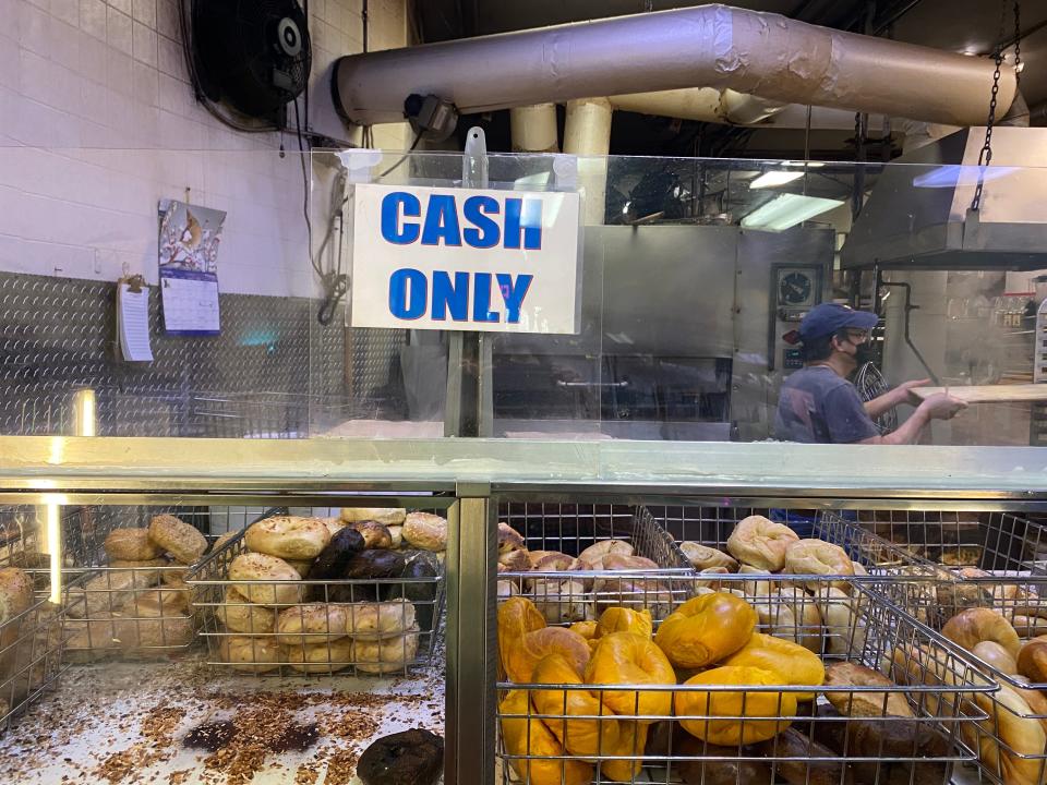 A counter with a display of bagels underneath and "cash only" sign placed above it.