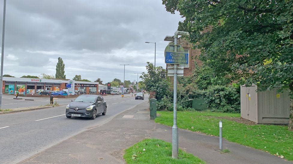 A sign saying cyclists rejoin carriageway next to a busy road