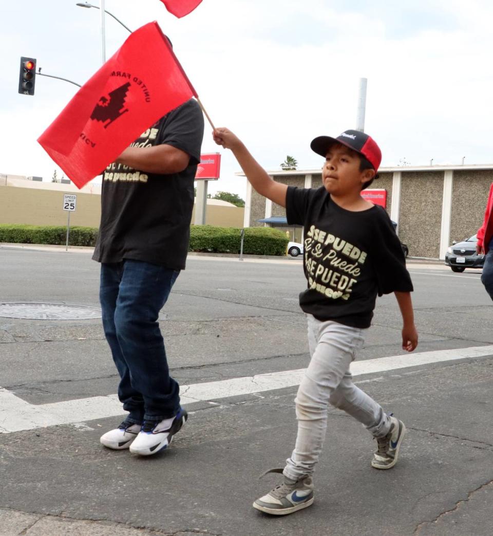 A boy waves a UFW flag while walking downtown during the Fresno May Day Immigratiom Reform rally/march on May 1, 2023.