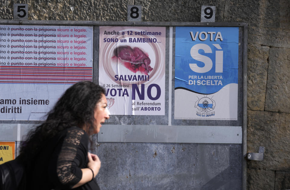 A woman walks past posters for the abortion referendum in San Marino, Sunday, Sept. 26, 2021. Tiny San Marino is one of the last countries in Europe which forbids abortion in any circumstance — a ban that dates from 1865. Its citizens are voting Sunday in a referendum calling for abortion to be made legal in the first 12 weeks of pregnancy. (AP Photo/Antonio Calanni)