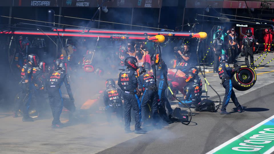 Mechanics deal with the smoke coming out of Verstappen's car in the pit lane. - Scott Barbour/Pool/AFP/Getty Images