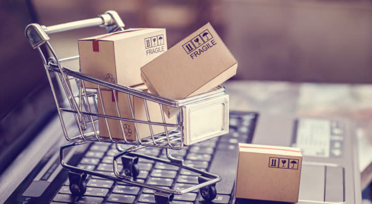 A miniature shopping cart is filled with cardboard boxes. e-commerce stocks