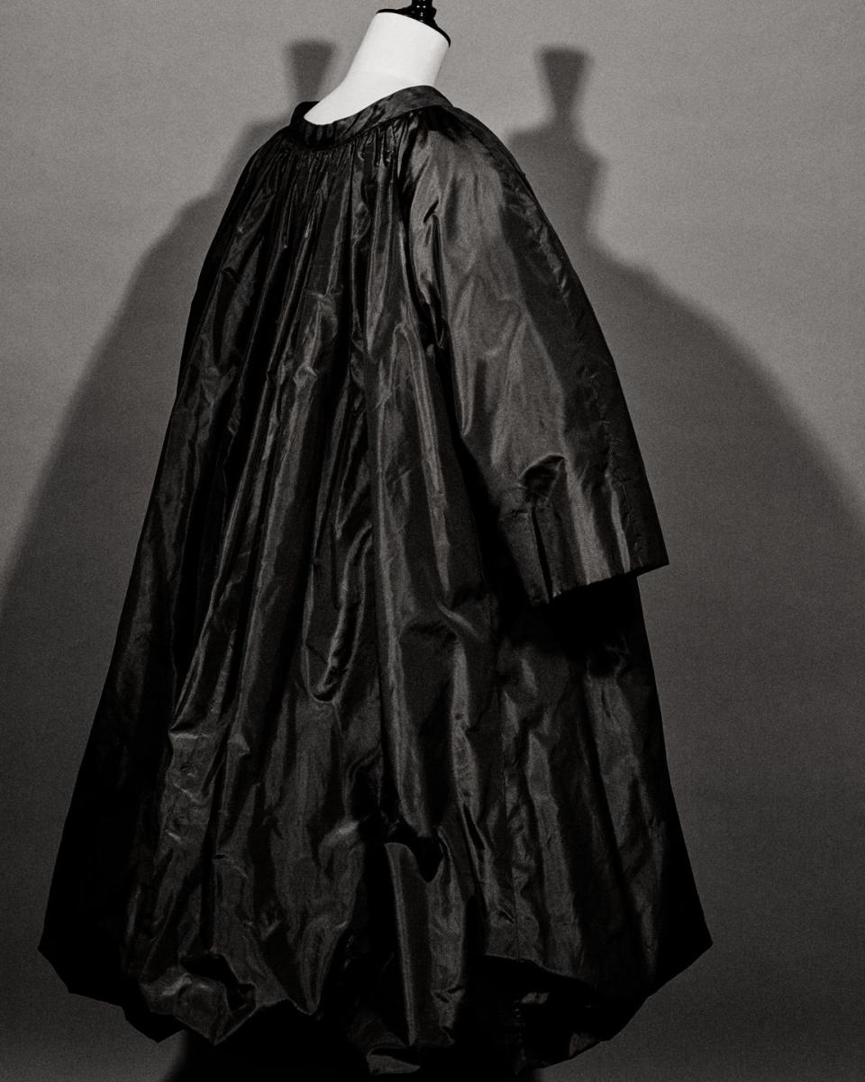 a black and white photo of a mannequin wearing a black coat