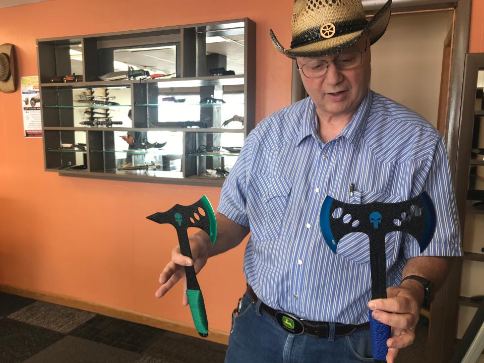 Ed Miller, owner of Fremont Cutlery Co., holds up a pair of throwing axes Saturday at the store's grand opening.