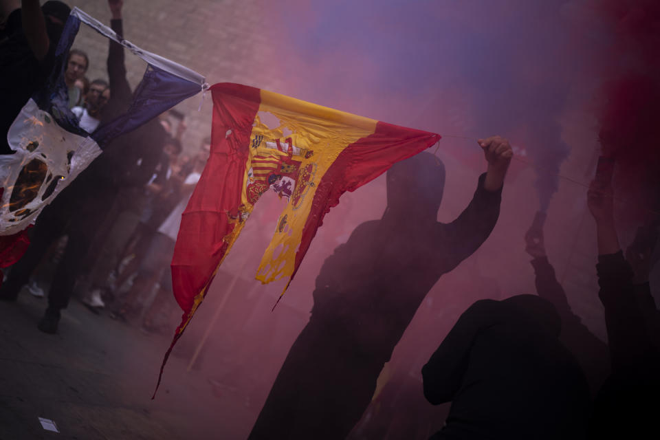 Protesters burn Spain and France flags as they take part in a demonstration during the Catalan National Day in Barcelona, Spain, Sunday, Sept. 11, 2022. Thousands of Spaniards who support the secession of Catalonia are gathering in Barcelona on the region's main holiday. (AP Photo/Joan Mateu Parra)