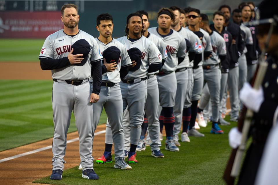 Cleveland Guardians players and coaches, led by new manager Stephen Vogt, line up for the national anthem before playing the Athletics on March 28 in Oakland.