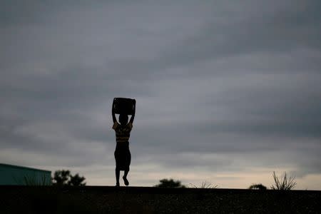 Storm clouds loom as a child carries water from a communal borehole near the capital Lilongwe, Malawi February 2, 2016. REUTERS/Mike Hutchings