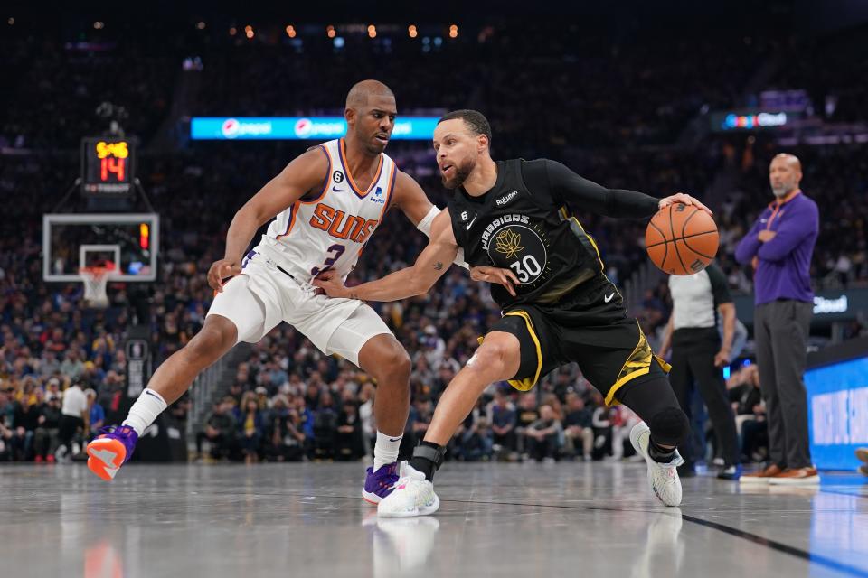Golden State Warriors guard Stephen Curry (30) dribbles the ball next to Phoenix Suns guard Chris Paul (3) in the second quarter at the Chase Center in San Francisco on March 13, 2023.