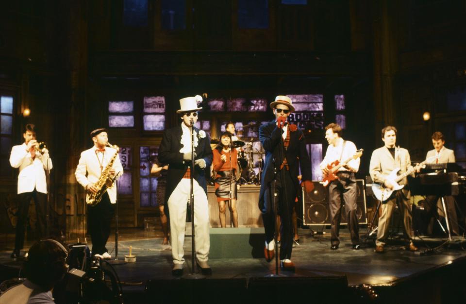 THEN: (L-R) Lee Thompson, Chas Smash, Suggs, Mark Bedford, Chris Foreman, Mike Barson of musical guest Madness perform on "Saturday Night Live" on April 14, 1984. (Photo by: Al Levine/NBC/NBCU Photo Bank)