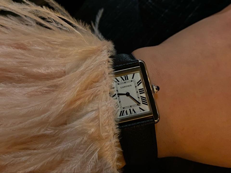 A lady wearing a Cartier watch with a feather sleeve