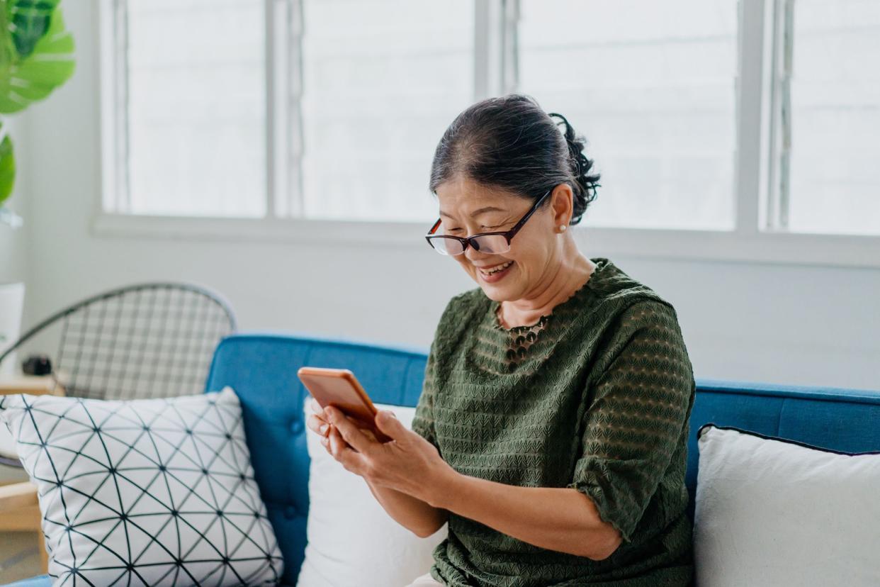 Image of a smile senior Asian Chinese woman using smartphone at home