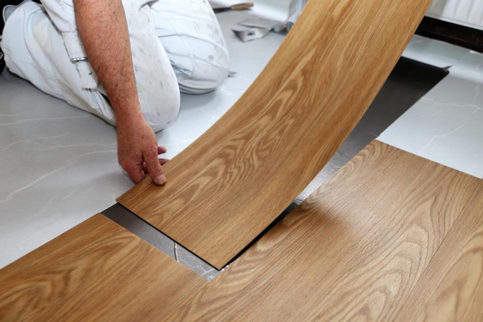 A worker lays down flooring.