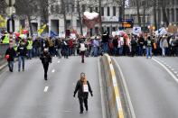 A protestor walks down the street with a balloon which reads 'where is the debate' during a demonstration against COVID-19 measures in Brussels, Sunday, Jan. 23, 2022. Demonstrators gathered in the Belgian capital to protest what they regard as overly extreme measures by the government to fight the COVID-19 pandemic, including a vaccine pass regulating access to certain places and activities and possible compulsory vaccines.(AP Photo/Geert Vanden Wijngaert)