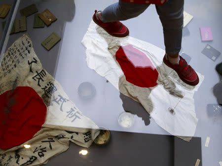 A visitor walks on a glass flooring above Japanese military flags seized by the Chinese People's Liberation Army (PLA) during World War Two, at the Museum of the War of Chinese People's Resistance Against Japanese Aggression, in Beijing, China, September 1, 2015, ahead of the commemoration of the 70th anniversary of the end of World War Two. REUTERS/Kim Kyung-Hoon