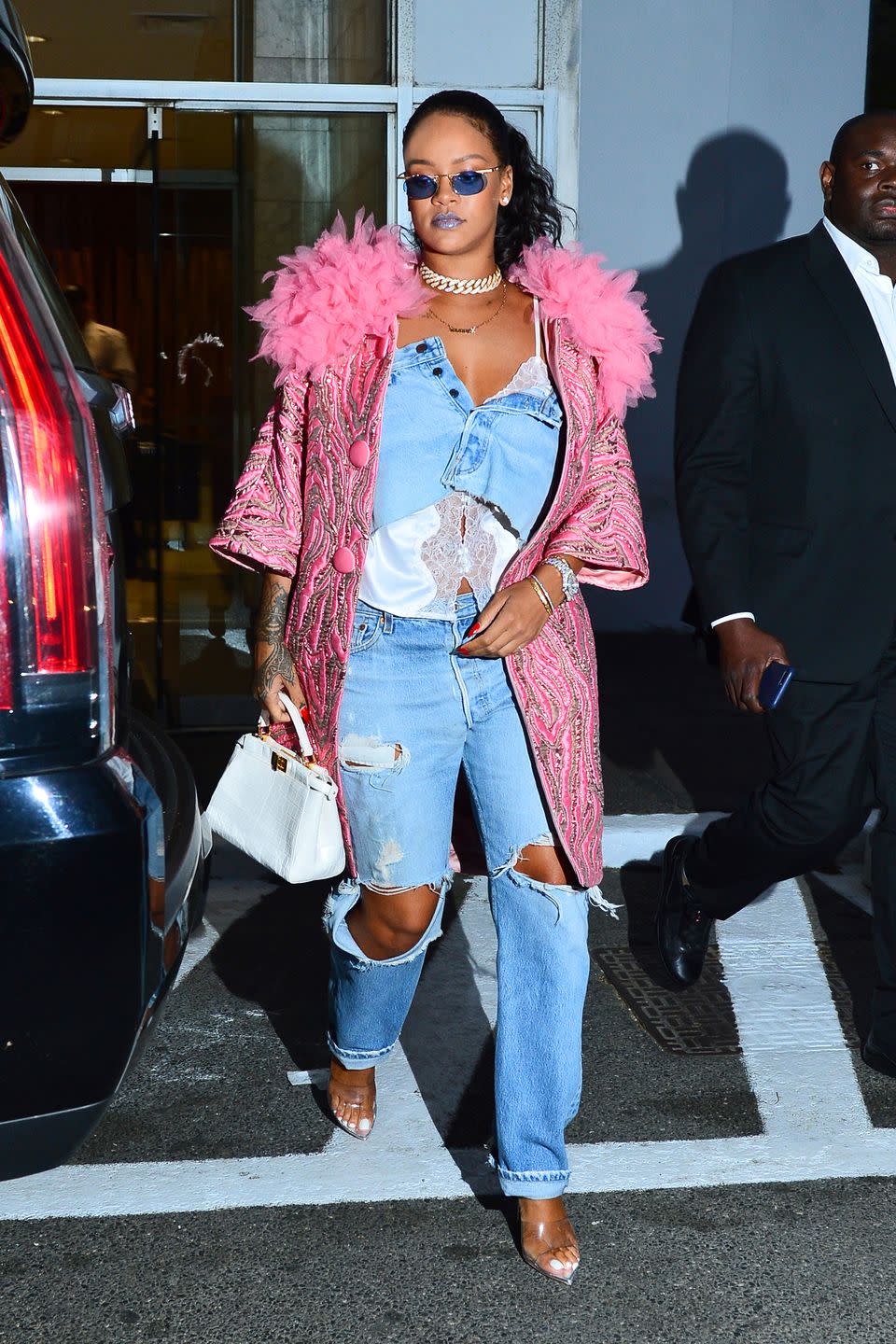 <p>in a denim skirt won as a top under a pink feather-boa-collared jacket, with distressed jeans, PVC heels, a white purse, and blue-tinted sunglasses while out in NYC.</p>