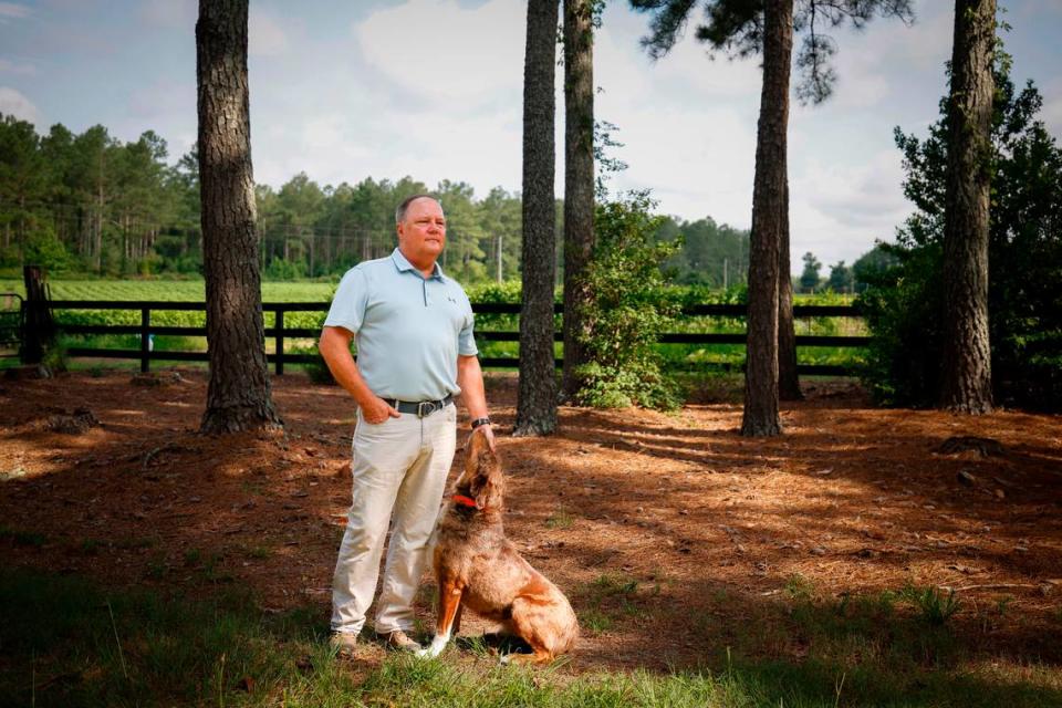 Eddie Huntley pets his dog, Levi, outside their Anson County home. Dozens of poultry barns have sprouted up near his home in recent years, bringing flies, vultures and a “really offensive” odor, he said.