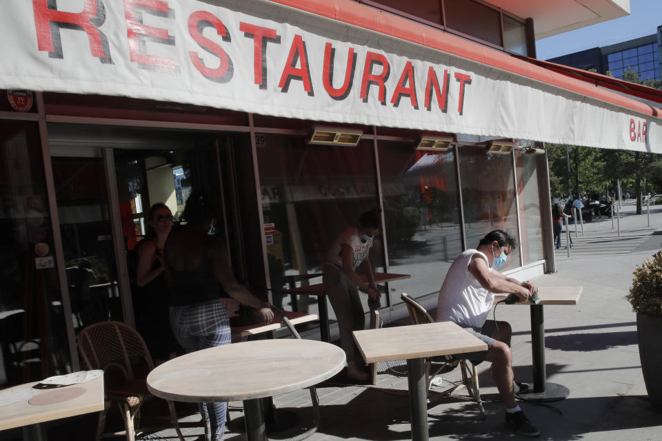 People prepare the terrace of their restaurant in Boulogne-Billancourt, outside Paris, Thursday, May 28, 2020. France is reopening its restaurants, bars and cafes starting next week as the country eases most restrictions amid the coronavirus crisis. Edouard Philippe defended the gradual lifting of lockdown up to now, saying the strategy was meant to avoid provoking a second wave. (AP Photo/Christophe Ena)