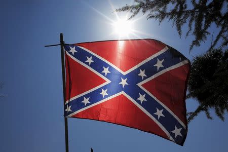 A Confederate flag is held up by a man at a rally outside the State House to get the Confederate flag removed from the grounds in Columbia, South Carolina June 23, 2015. REUTERS/Brian Snyder