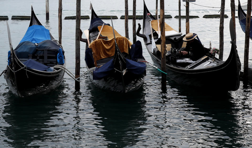 A Gondolier sits in his Gondola docked in St. Mark's square in Venice, Italy, Saturday, Jan. 30, 2021. Gondolas and other vessels are moored instead of preparing for Carnival's popular boat parade in the lagoon. Alleys are eerily empty. Venetians and the city's few visitors stroll must be masked in public places, indoors and out, under a nationwide mandate. (AP Photo/Antonio Calanni)