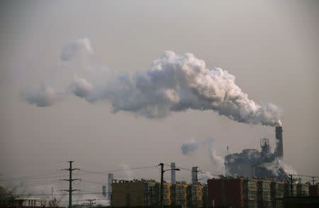 Smoke rises from a chimney of a steel plant next to residential buildings on a hazy day in Fengnan district of Tangshan, Hebei province in this February 18, 2014 file photo. REUTERS/Petar Kujundzic/Files