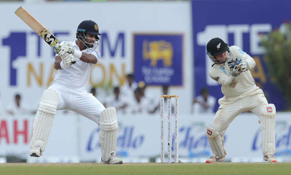 Sri Lanka's Dimuth Karunaratne plays a shot as BJ Watling watches during the fourth day of the first test cricket match between Sri Lanka and New Zealand in Galle, Sri Lanka, Saturday, Aug. 17, 2019. (AP Photo/Eranga Jayawardena)
