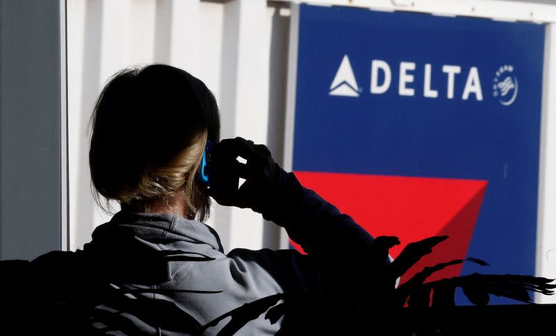 FILE PHOTO: A passenger talks on her phone at a Delta Airlines gate at the Salt Lake City international airport