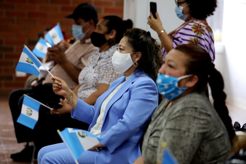 LOS ANGELES, CA - MAY 10: Elizabeth Lopez, center, of Los Angeles, waves a Guatemalan flag while musicians play a restored marimba celebrating Mother's Day, Latin America celebrates on May 10th, at the Consulate General of Guatemala on Monday, May 10, 2021 in Los Angeles, CA. Rosauro Esteban, restored the marimba that was in ruins at the Guatemalan consulate. (Gary Coronado / Los Angeles Times)