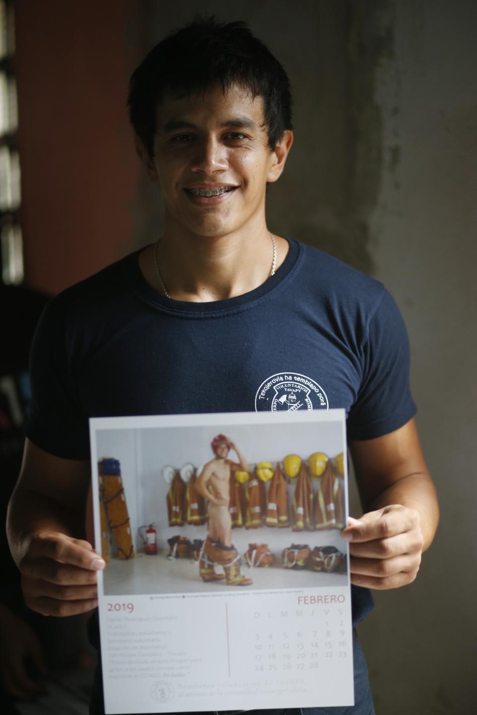 In this Jan. 12, 2019 photo, firefighter Daniel Rodriguez poses holding a calendar page with a nude photo of himself, in Asuncion, Paraguay. The caption at the bottom of every photograph reads: "I've stripped for this image because that's how the State keeps us: buck naked." (AP Photo/Jorge Saenz)