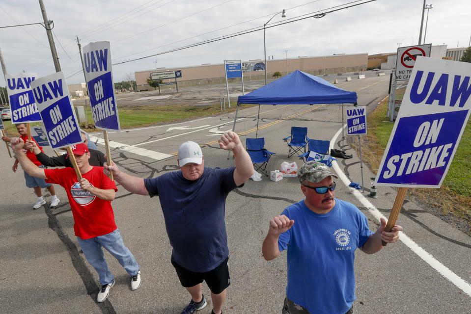 FILE - In this Sept. 16, 2019, file photo picketers carry signs at one of the gates outside the closed General Motors automobile assembly plant in Lordstown, Ohio. Many from Lordstown, Ohio, and near Baltimore and Detroit are opposing a deal that could end a 37-day strike that crippled GM’s U.S. production and cost the company an estimated $2 billion. (AP Photo/Keith Srakocic, File)