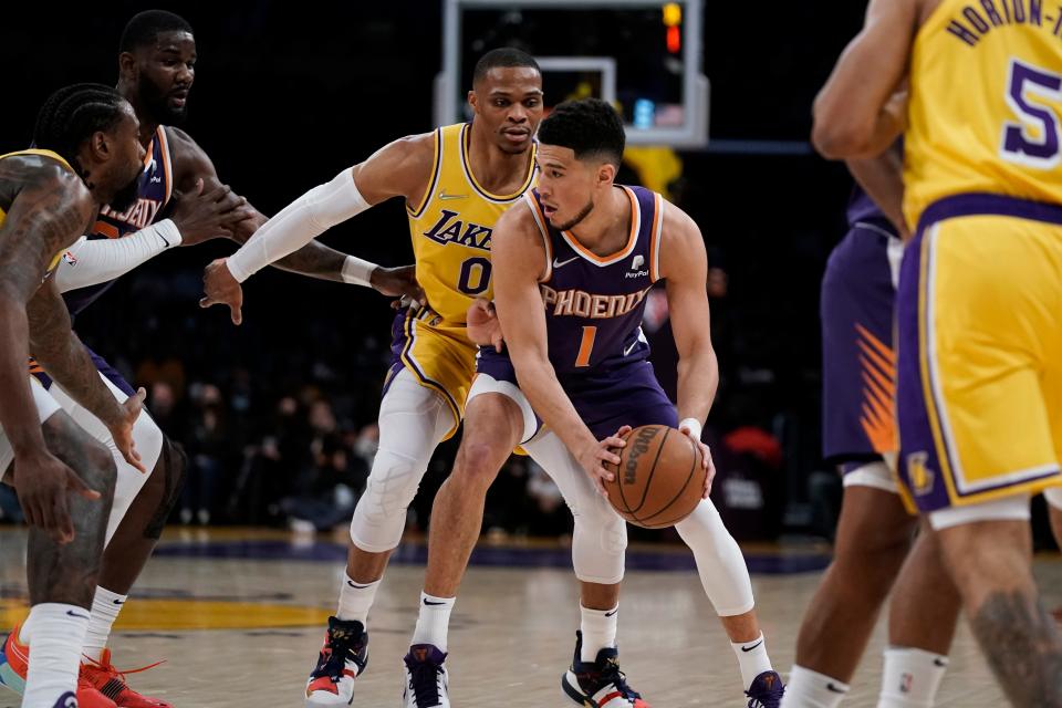 Phoenix Suns' Devin Booker, center right, is pressured by Los Angeles Lakers' Russell Westbrook during first half of an NBA basketball game Tuesday, Dec. 21, 2021, in Los Angeles. (AP Photo/Jae C. Hong)