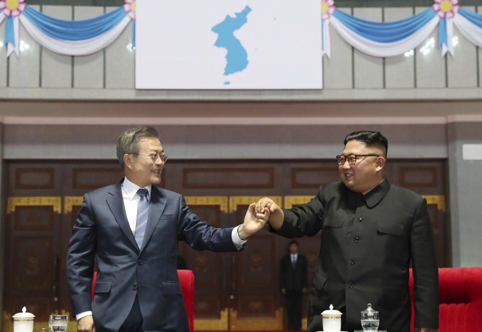 South Korean President Moon Jae-in, left, and North Korean leader Kim Jong Un hold their hands after watching the mass games performance of "The Glorious Country" at May Day Stadium in Pyongyang, North Korea, Wednesday, Sept. 19, 2018. Unification flag symbol at top centre.(Pyongyang Press Corps Pool via AP)