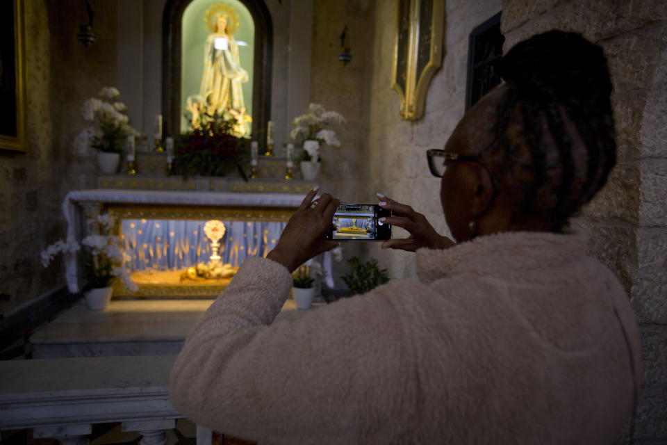 In this Thursday, Dec. 5, 2019, photo, a Christian visitor takes a picture of a wooden relic believed to be from Jesus' manger inside the Church of the Nativity, traditionally believed by Christians to be the birthplace of Jesus Christ, in the West Bank city of Bethlehem. As visitors descend on Bethlehem this Christmas, they have the option of staying in restored centuries-old guesthouses, taking food tours of local markets, and perusing the dystopian art in and around a hotel designed by the British graffiti artist Banksy.(AP Photo/Majdi Mohammed]=[[[[[[[[[[[[[[