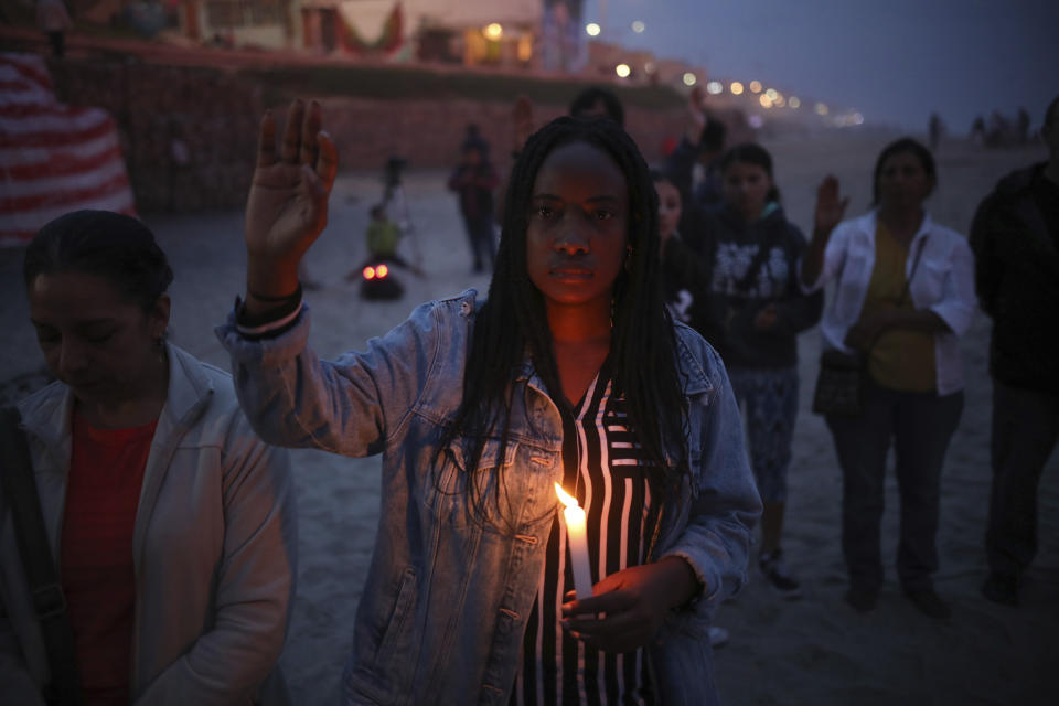 A woman holding a candle observes one minute of silence in memory of migrants who have died during their journey toward the U.S., a few steps from the border fence that separates Mexico from the United States, in Tijuana, Mexico, late Saturday, June 29, 2019. (AP Photo/Emilio Espejel)