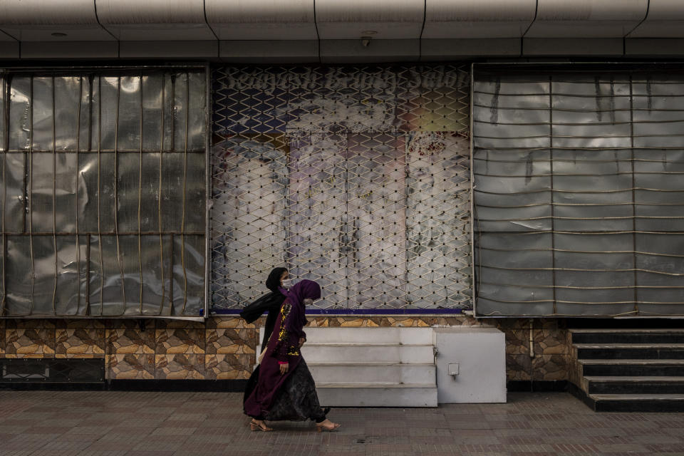 Afghan women walk past a closed beauty salon in Kabul, Afghanistan, Saturday, Sept. 11, 2021. Since the Taliban gained control of Kabul, several images depicting women outside beauty salons have been removed or covered up. (AP Photo/Bernat Armangue)