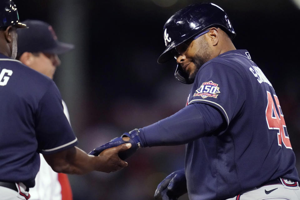 Atlanta Braves' Pablo Sandoval, right, is congratulated by first base coach Eric Young Sr. after his third single of the night, during the sixth inning of the team's baseball game against the Boston Red Sox at Fenway Park, Tuesday, May 25, 2021, in Boston. (AP Photo/Charles Krupa)