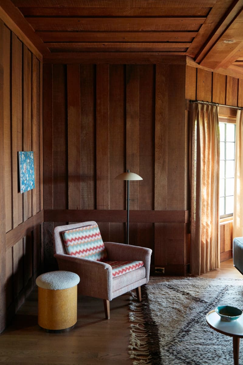 Armchair and lamp in wood paneled living room.