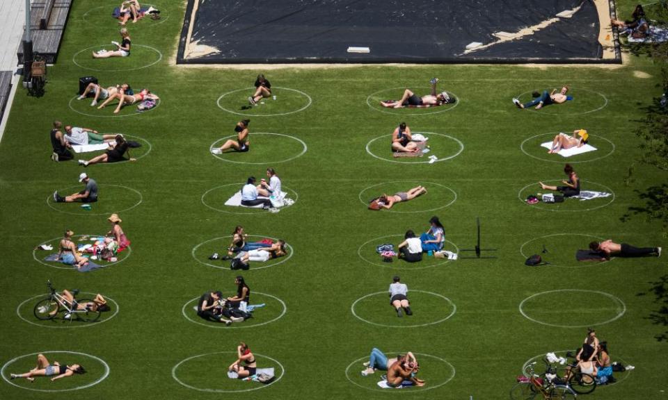 People sit inside social distancing markers at Domino Park in Brooklyn this week.