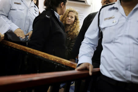Palestinian teen Ahed Tamimi enters a military courtroom escorted by Israeli security personnel at Ofer Prison, near the West Bank city of Ramallah, February 13, 2018. REUTERS/Ammar Awad